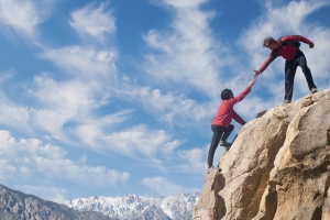 A partner puts out a helping hand up the summit.