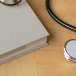 Image of a Stethoscope and Book for World Cancer Day Employment Article