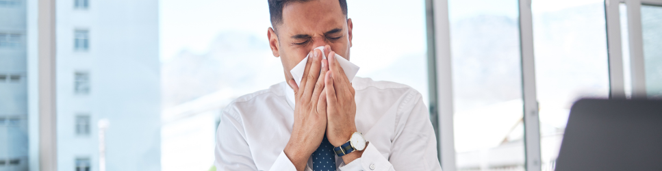 Image of an office worker blowing their nose for article header image