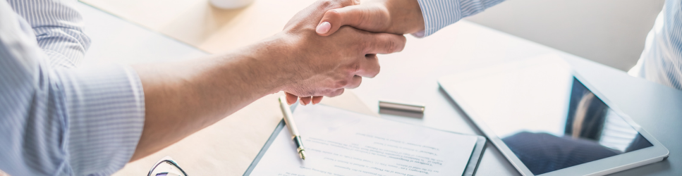 Image of staff shaking hands over an updated employment contract
