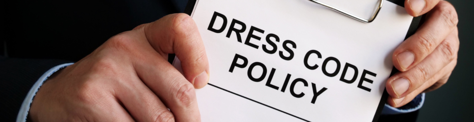 Image of a worker holding a sign which reads 'Dress code policy'