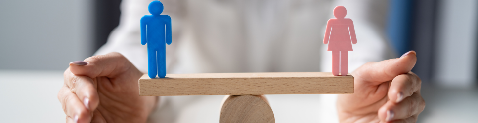 Image of male and female symbols balancing on a desk for gender pay gap header