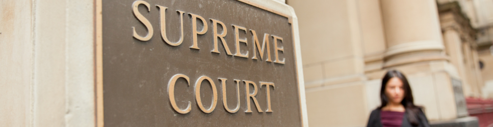 Image of supreme court sign with a solicitor standing in the background as page header image
