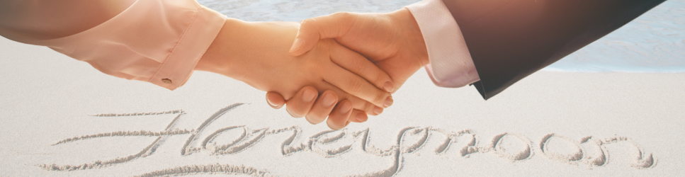 Image of shaking hands with honeymoon written in sand in the background for Postnuptial agreements header image