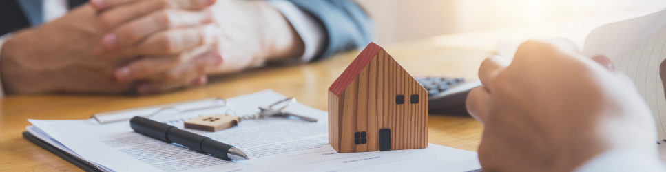 Image of an estate planning meeting with life insurance policy and house on the table.