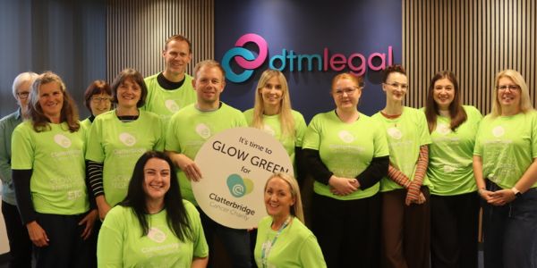 Photo of the DTM Legal team with Clatterbridge Cancer Charity - Glow Green for Clatterbridge sign